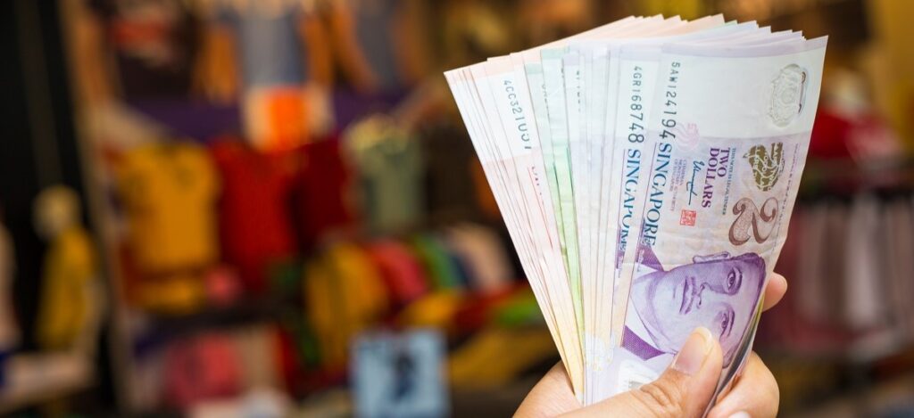 Hand holding Singapore dollar notes, representing how to secure a fast personal loan in Singapore without hassle.