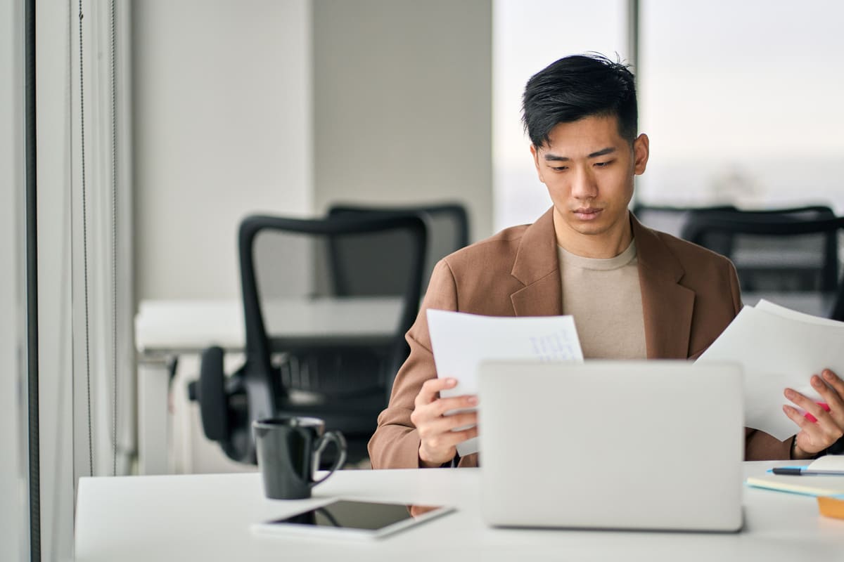 Man on a work permit reviewing documents at his desk, representing eligibility and considerations for taking a personal loan while working in Singapore.