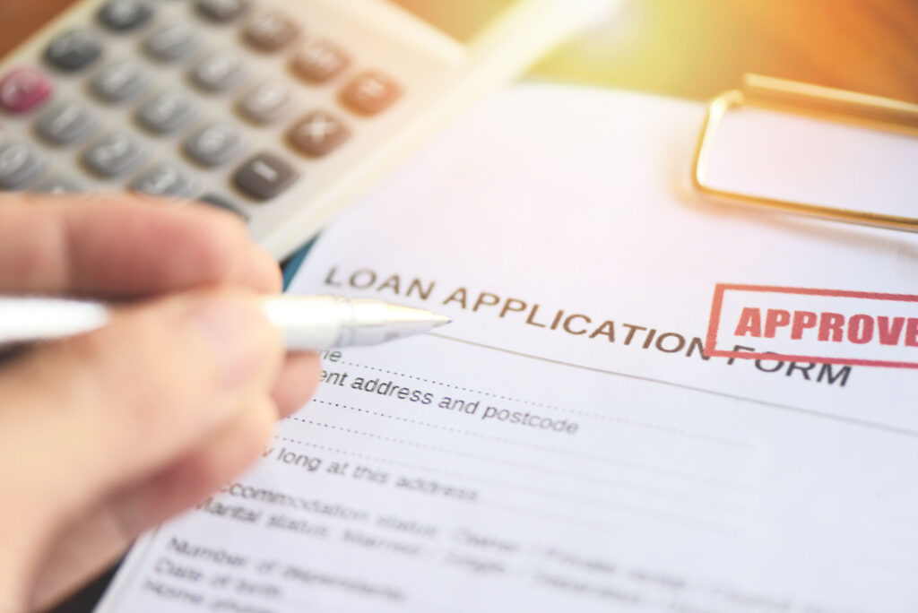 Loan application form marked approved with pen and calculator, representing fast approval loans and factors lenders check beyond credit score.