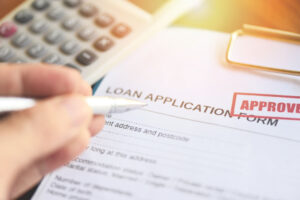 Loan application form marked approved with pen and calculator, representing fast approval loans and factors lenders check beyond credit score.