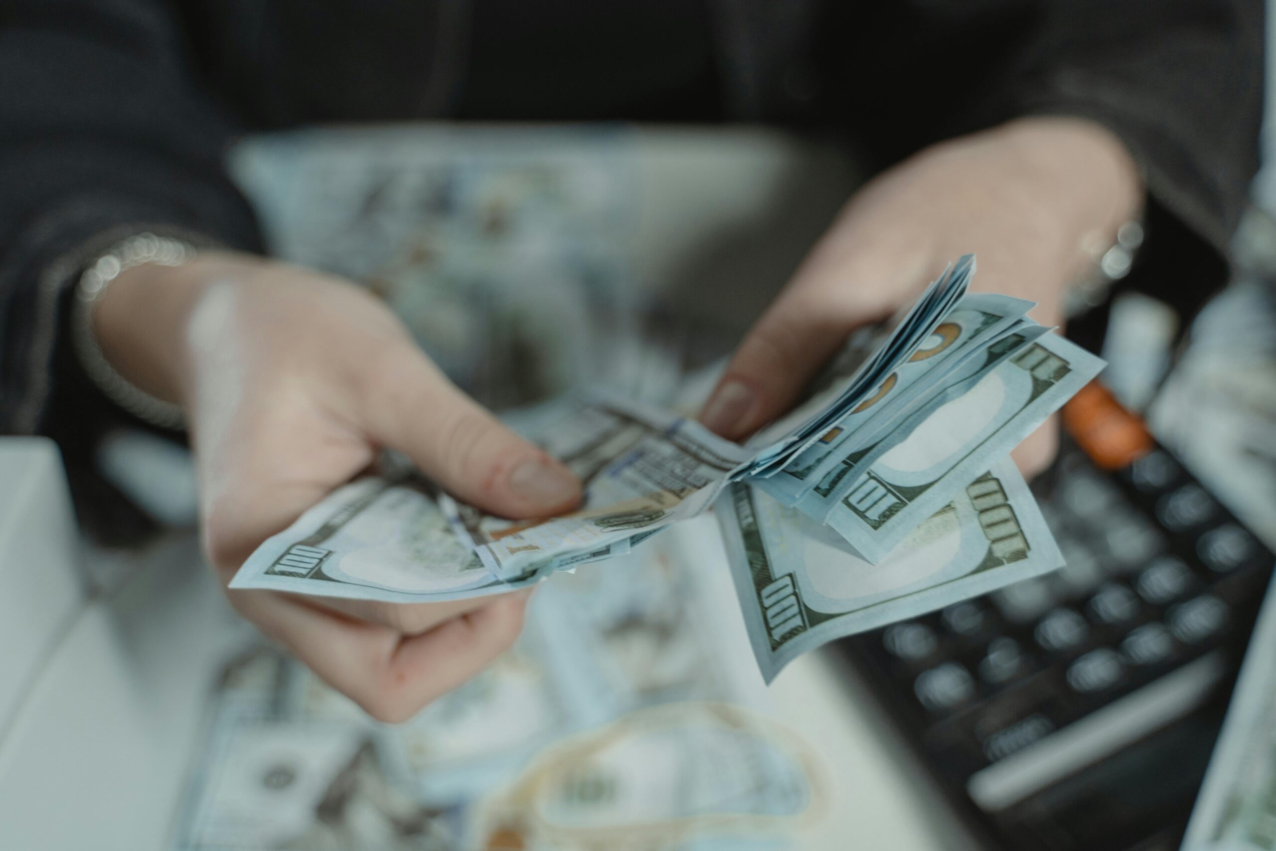 Hands counting cash beside a calculator, representing fast cash loans, instant approval options, and quick financial assistance in Singapore with Fast Money.