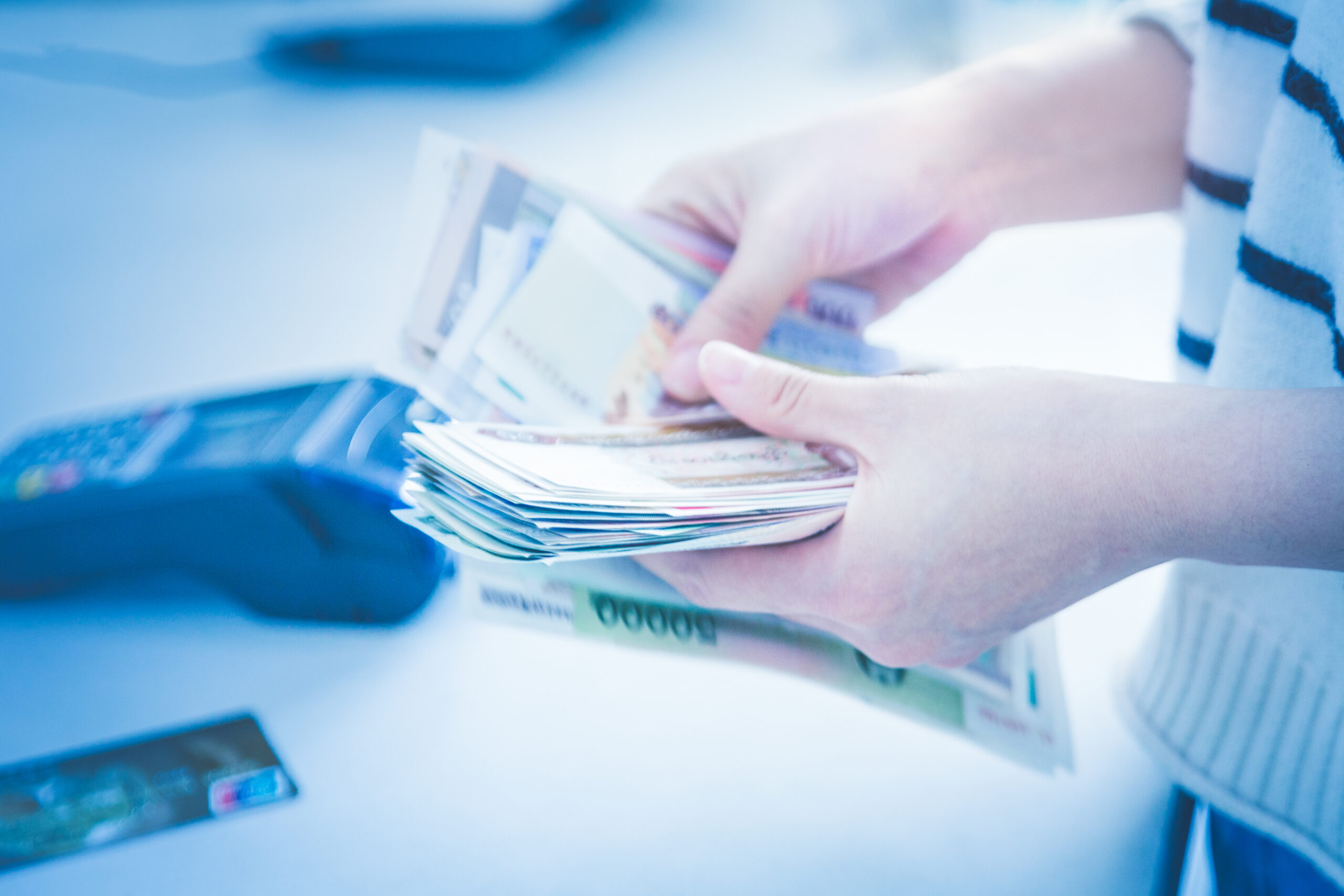 Business owner counting cash to manage small business cash gaps while exploring alternative financing options for everyday operations.