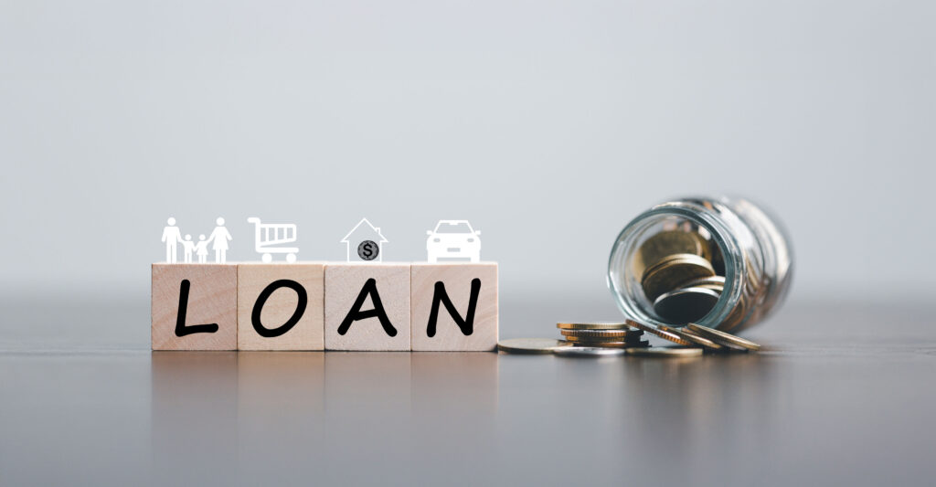 Loan cost concept with wooden blocks spelling LOAN, financial icons, and coins spilling from a jar, illustrating hidden loan fees, interest charges, and borrowing costs in Singapore.