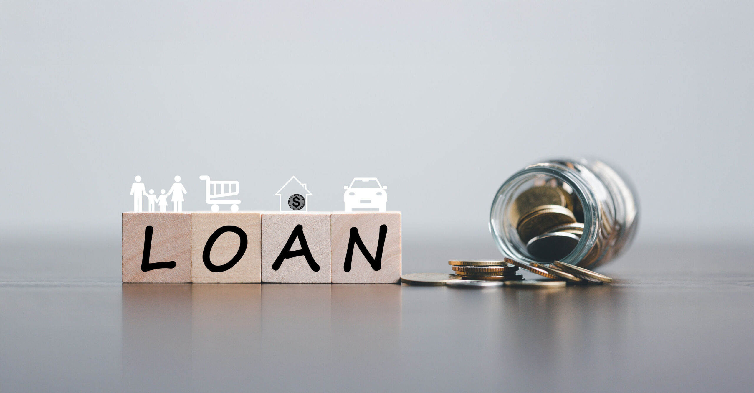 Loan cost concept with wooden blocks spelling LOAN, financial icons, and coins spilling from a jar, illustrating hidden loan fees, interest charges, and borrowing costs in Singapore.