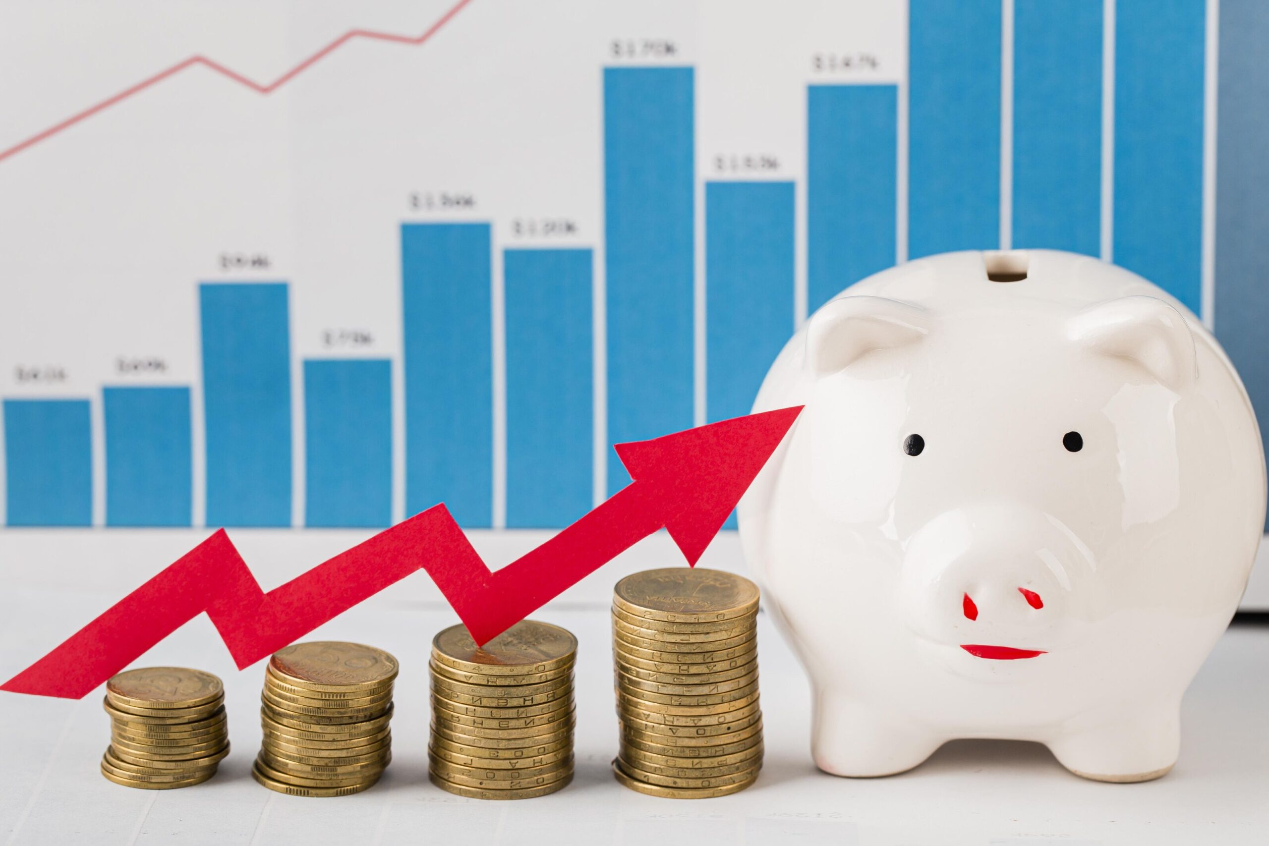 Piggy bank beside stacks of coins with a red upward arrow and financial growth chart in the background