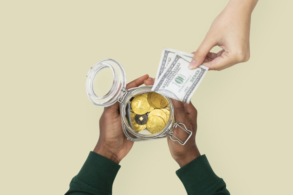 Emergency borrowing and financial decision-making under pressure, illustrated by hands placing cash into a jar of coins.