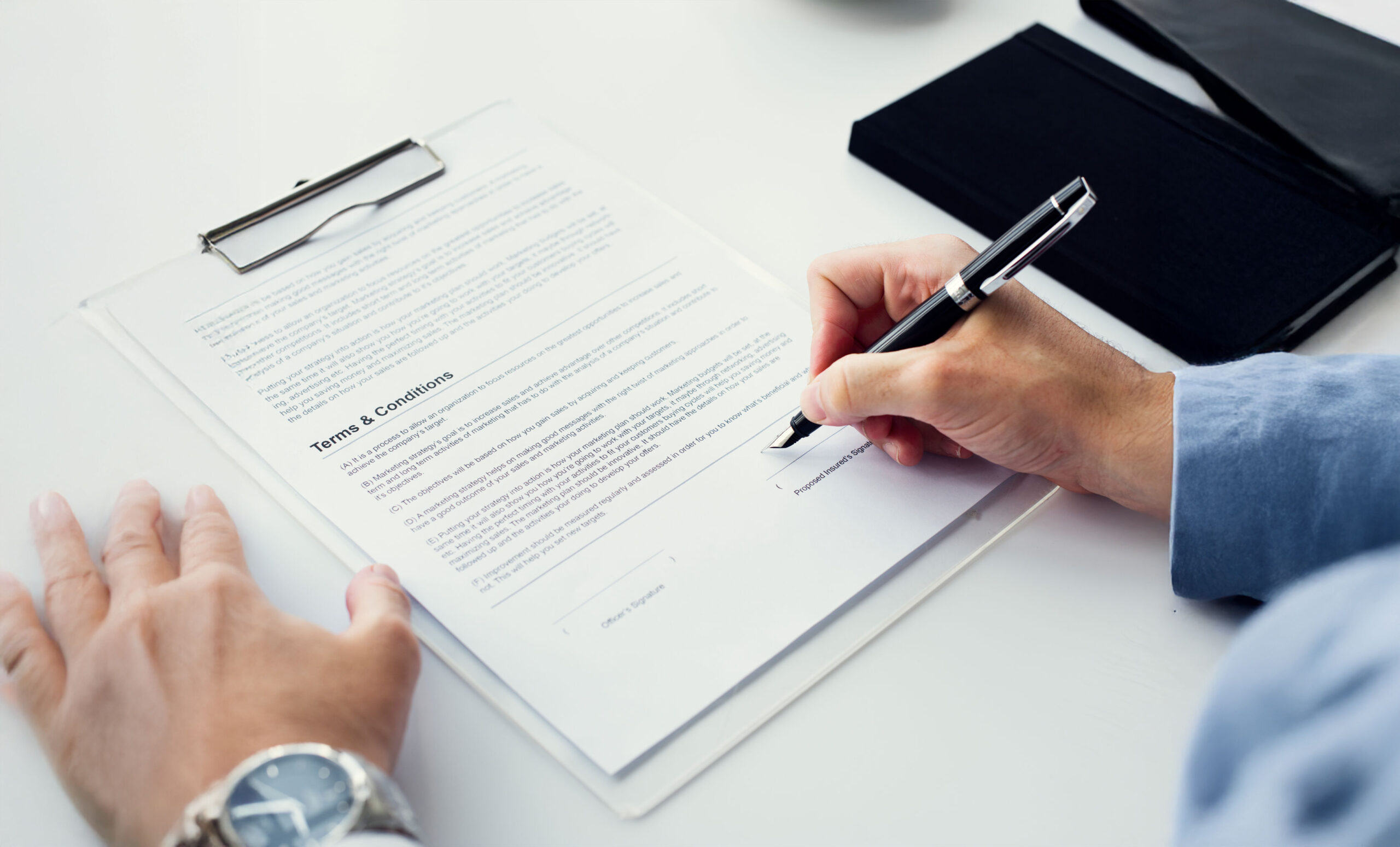 Person reviewing and signing a loan contract, highlighting key terms and conditions to check carefully before signing a loan agreement.